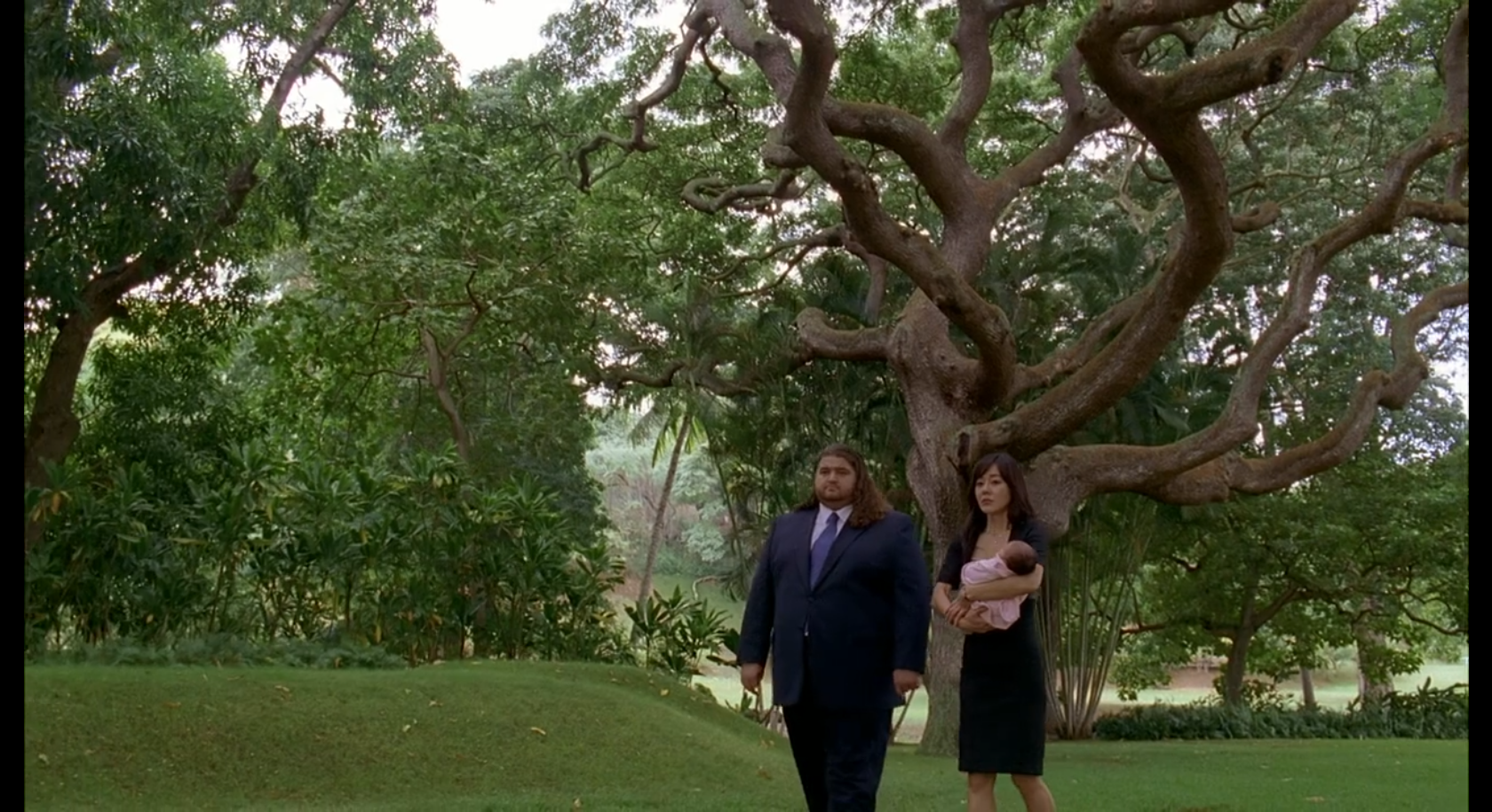 Hurley and Sun (holding Ji Yeon) stand before a beautiful tree in a cemetery.