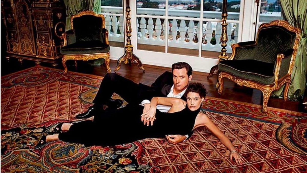 Gavin Newsom poses on his oriental rug in his lavish home, lying down with then-wife Kimberly Guilfoyle, looking like the Platonic ideal of "rich douchebag"