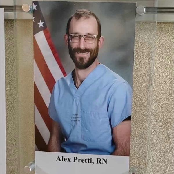 A staff photo of a smiling Alex Pretti, RN, in nurse's scrubs, is pinned to a board