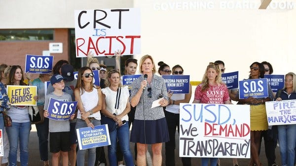 A group of white protesters hold signs protesting CRT.