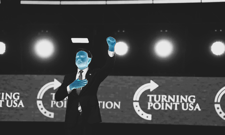 JD Vance gives what appears to be a perversion of the black power sign at Turning Point USA's convention. The photo is black and white. His hands and face have had the color inverted